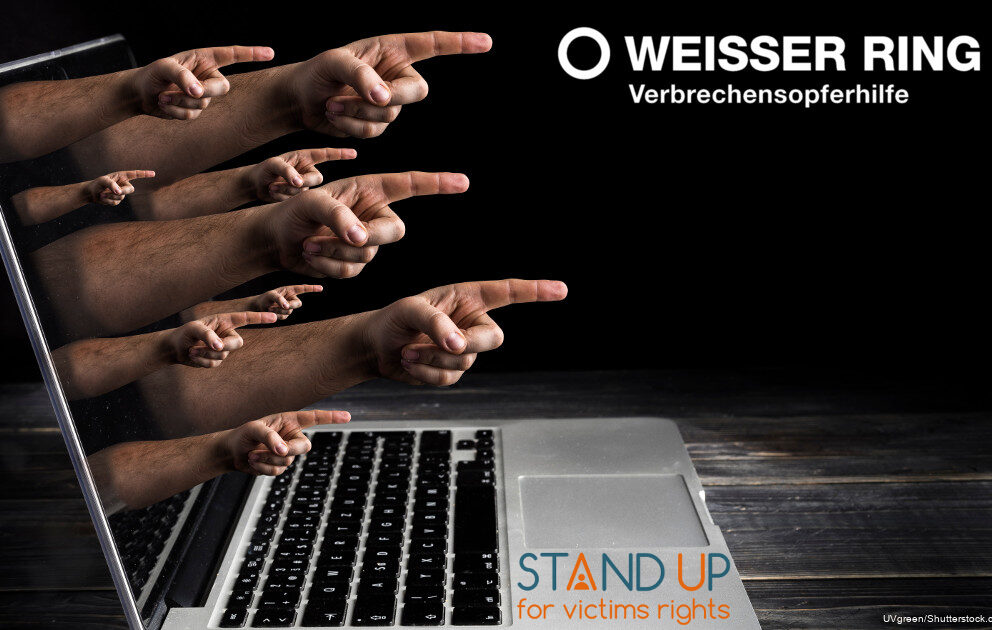 Das Bild von einem Laptop und aus dem Bildschirm heraus gehen Hände die mit dem Zeigefinger aus dem Laptop heraus zeigen. Im rechten oberen Eck steht "Weisser Ring und Verbrechensopferhilfe" und unten steht "Stand up for victims rights"